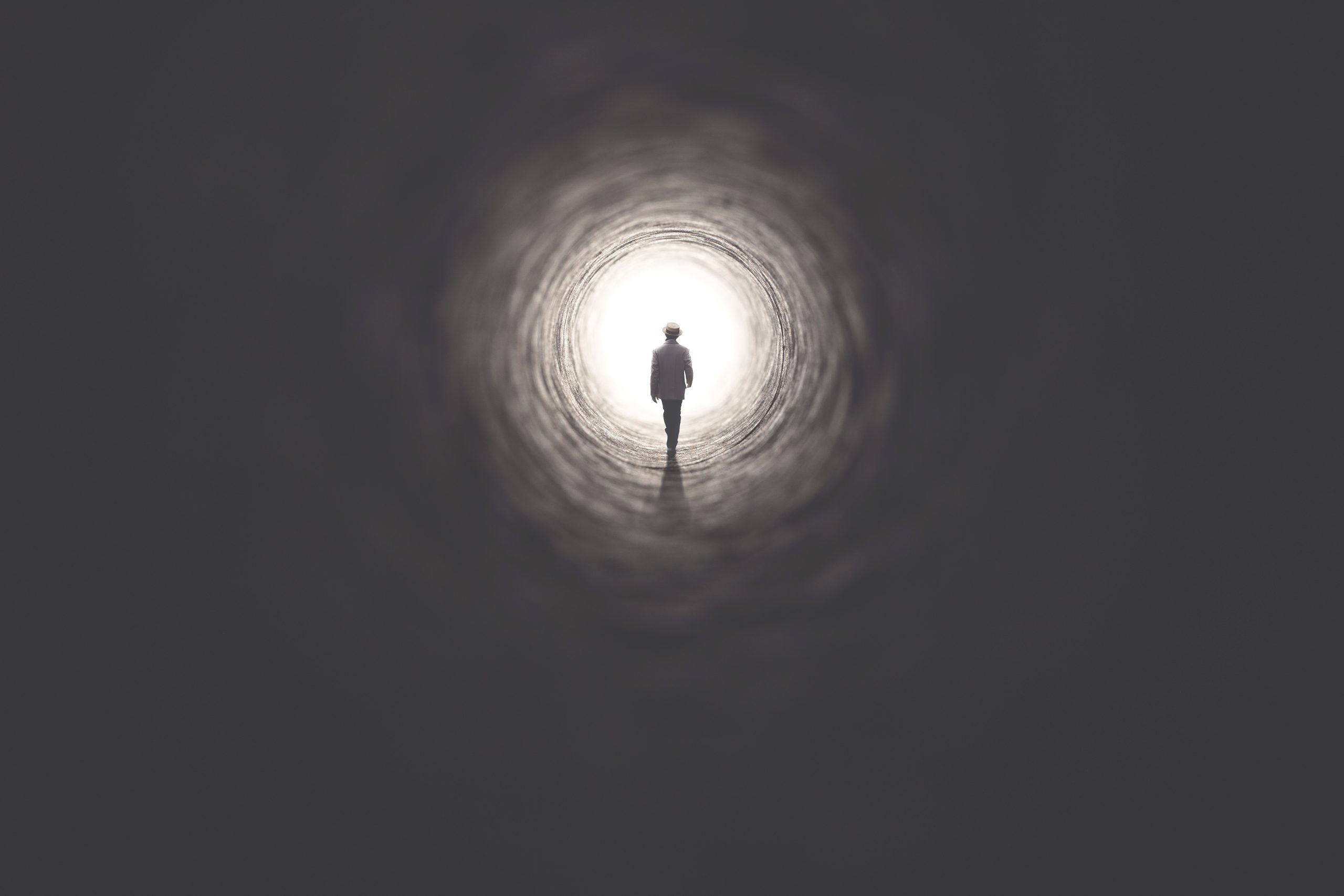Man walking out of the dark tunnel toward the light