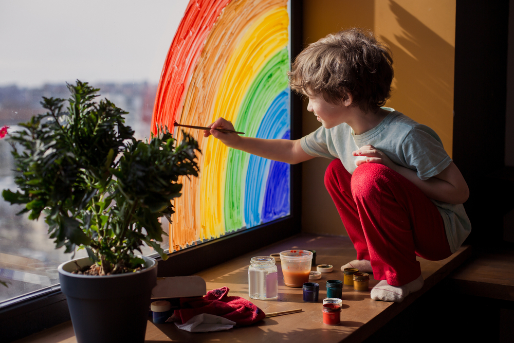 Child draws a rainbow on the window