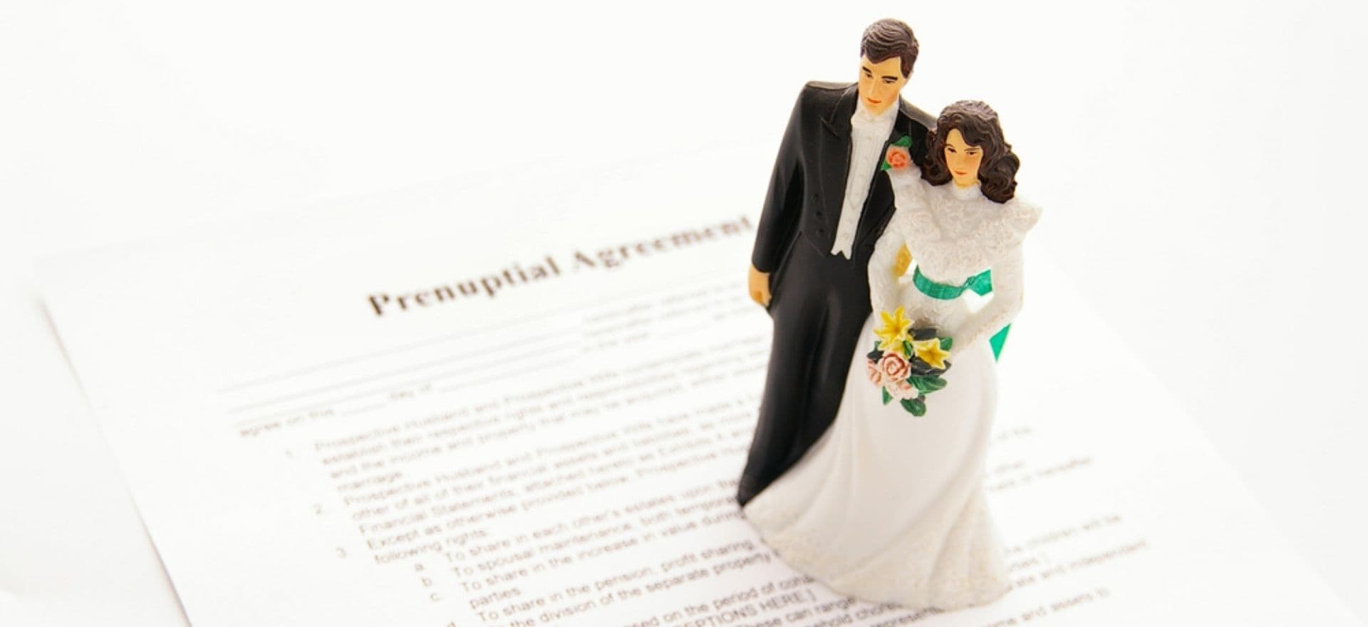 Wedding caketopper figurine on top of prenuptial agreement