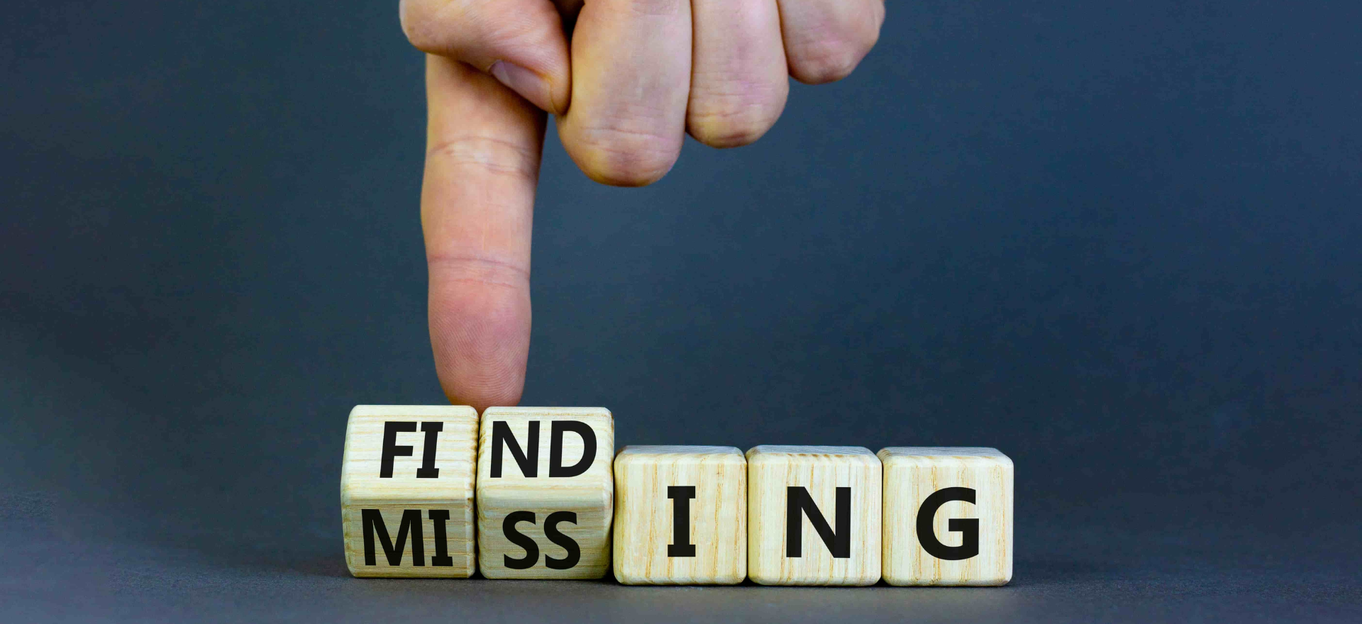 A finger changing wooden cubes with word missing to finding